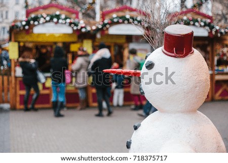 Snowman in the foreground, in the background Christmas market. Conceptual photo of the celebration of Christmas. Celebratory concept.