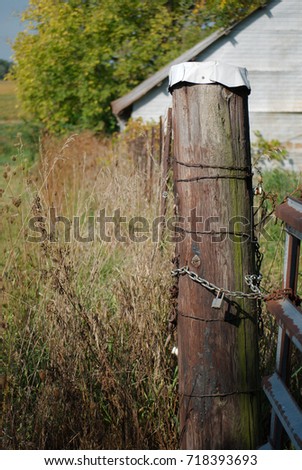 Post for locking a gate with attached barbed wire fence. Northern Illinois, USA.