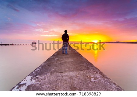 The sunset at jetty with a men view from back as point of interest. Beautiful and majestic color of sunset.