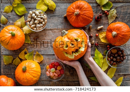 Carved smiling halloween pumpkin head among pumpkins on wooden background top view