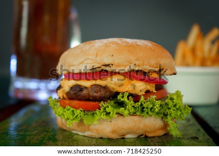 Cheeseburger with tomato, onion, mustard and ketchup, poppy seeds on top bun , on red wooden table