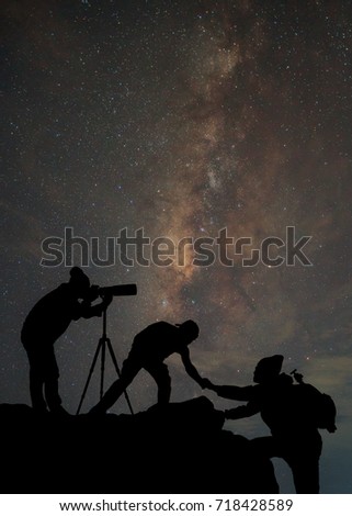 friends helping each other and with teamwork trying to reach the top of the mountains during wonderful the milky way background, Thailand.