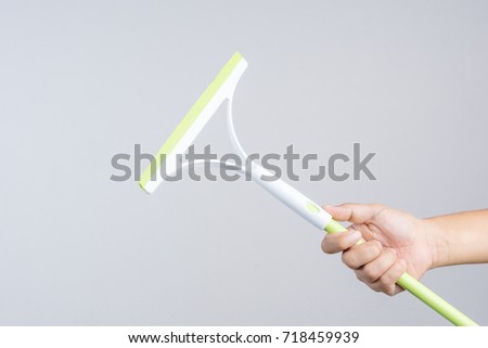 Hand holding window cleaning tool,glass wiper or wet floor cleaner, rubber with plastic handle  on white background