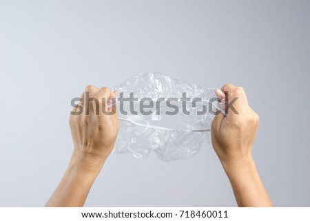 Hand holding disposable transparent plastic shower cap on white background Royalty-Free Stock Photo #718460011