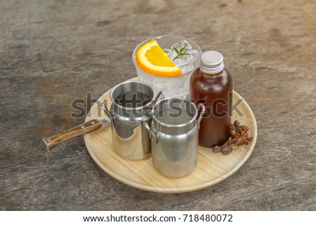 The set of Asian coffee with iced glass and piece of tangerine on top and mug of coffee and other decorative stuff such as brown bottle , coffee bean and anise.