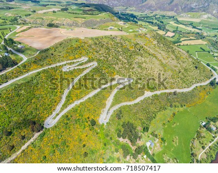 Winding Road on Mountains near Queenstown, New Zealand from aerial view by drone flying over Crown Range Road east of Queenstown in Otago, South Island of New Zealand.