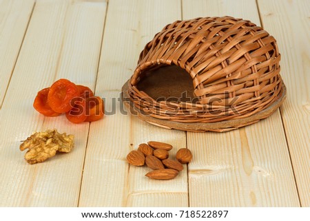 A wicker house and a treat for a hamster. Nuts, dried apricots.