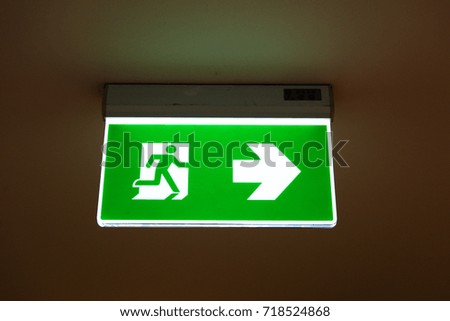 green emergency exit sign showing the way to escape