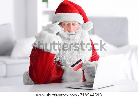 Santa Claus with laptop and credit card at home