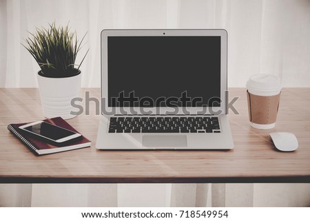 Laptop with smart phone notebook and coffee cup on workplace table.