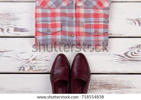 Cropped photo of plaid shirt and leather shoes on light wooden background. Clothing and footwear, good pic for web store.