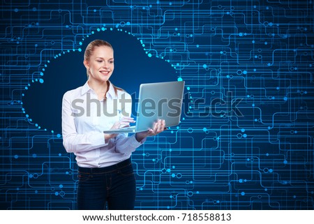 Cheerful young woman using laptop on abstract blue circuit background. Cloud computing concept 