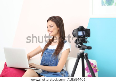 Young female blogger recording video on camera at home