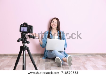 Young woman recording video near color wall