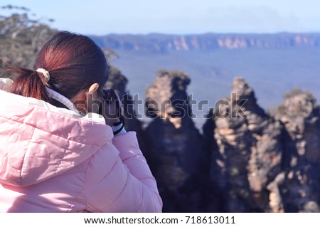 Young girl taking photo and enjoying scenic view of Three Sisters rock formation in the Blue Mountains National Parks near Sydney, New South Wales, Australia,