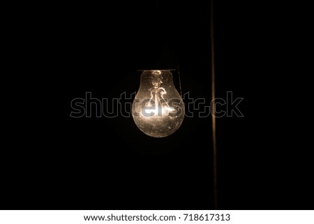 A dim bulb in the middle of the night hung on a wall in a garden shed