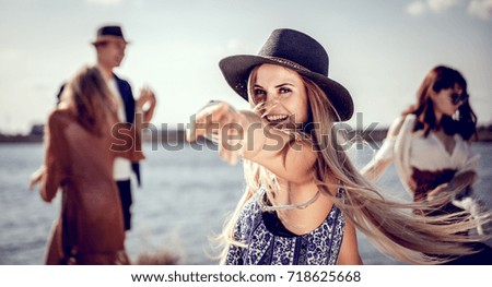 Beautiful styled hippie girl dancing at the beach with group of friends