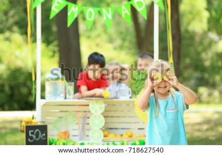 Funny little girl near lemonade stand in park