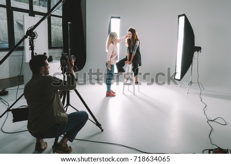 professional photographer, makeup artist and beautiful model on fashion shoot in photo studio with lighting equipment   Royalty-Free Stock Photo #718634065