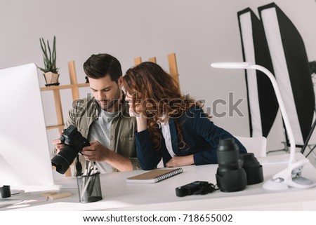 male photographer and model choosing photos for portfolio in modern office
