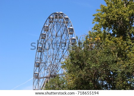 Metal construction / Ferris wheel in the park / Attraction on a background of clear sky and trees