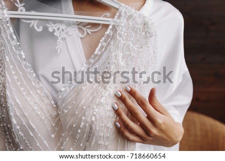 Bride.Preparations.Wedding.Manicure. Bride touch beads on your white wedding dress by hand with pearl nails. Royalty-Free Stock Photo #718660654