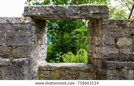One old stone wall with a window looking out over trees. Taken in Rothenburg Ob Der Tauber in Germany.