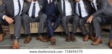 Groom and Groomsmen Sitting on Sofa Royalty-Free Stock Photo #718696570