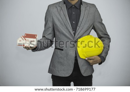 Businessman show house model in his hand and yellow hat engineering on white background