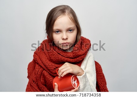 little girl in warm scarf in hand mug on light background portrait, ill with flu, health, treatment                               