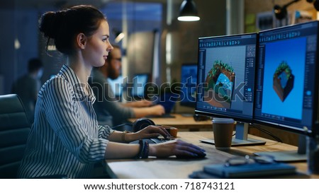 Female Game Developer Works on a Level Design on Her Personal Computer with Two Displays. She works in a Creative Office Space. Royalty-Free Stock Photo #718743121