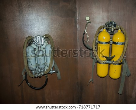 two old, retro, vintage, aged Aqualung or Scuba Oxygen Balloons hang on wooden wall. photo of yellow Diving Equipment. Underwater sport item. dive tool