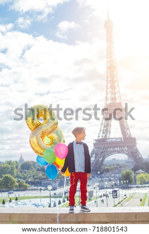 Happy boy with bunch of colorful balloons in Paris near the Eiffel tower.