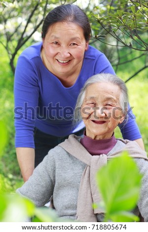 picture of one mature Chinese woman with her senior mother outdoor in the yard