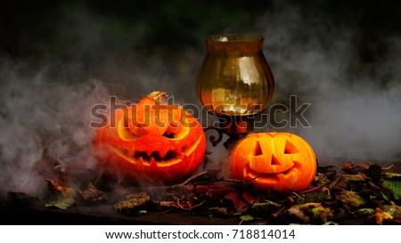 Halloween pumpkins on the wooden table. Lamp, leaves and candlestick on the background. Spooky forest.