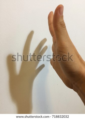 A hand and a shadow touching on a white background