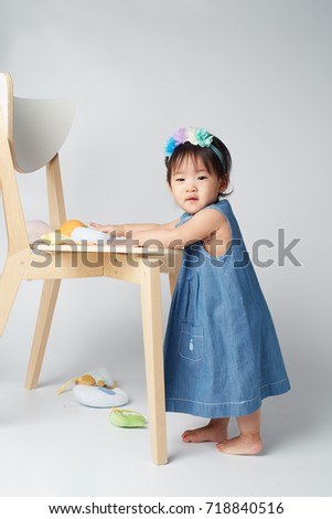 Adorable Baby Asian Girl On Blue Skirts Stand Up Pose With White Chair  And Costume Fashion Set