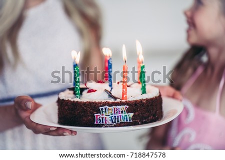 Happy family is celebrating little daughter's Birthday. Cropped image of attractive young woman with her charming daughter in pink dress on kitchen.