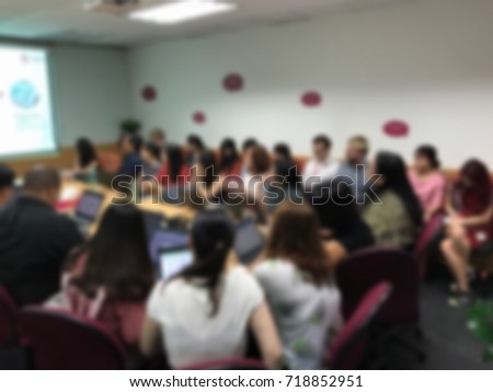 Blur photo of lots of (crowded) people sitting in a meeting room of a workshop / meeting / conference / study