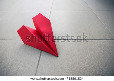 The red paper aircraft drop on flat concrete pathway. Vignette picture tone 