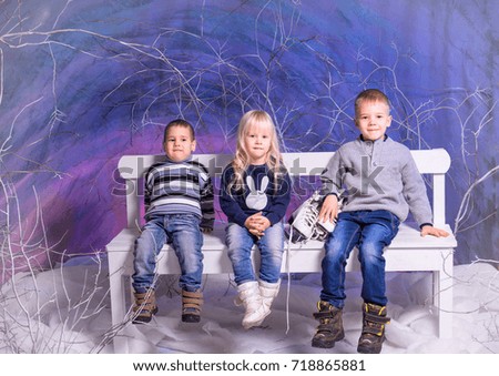 Three children sitting on bench in winter time.