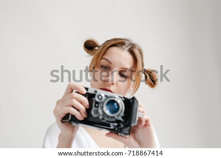 Close up portrait of a smiling pretty girl taking photo on a retro camera isolated over white background.