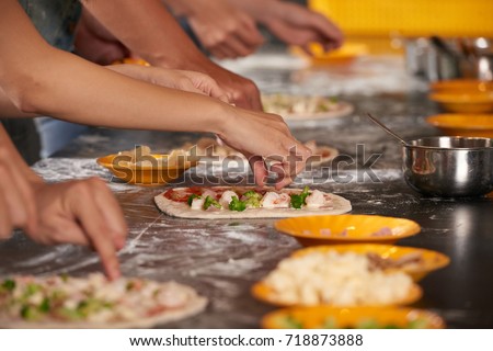 Hands of people making pizzas together Royalty-Free Stock Photo #718873888