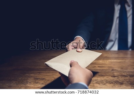 A man giving bribe money in a brown envelope to another businessman in a corruption scam Royalty-Free Stock Photo #718874032