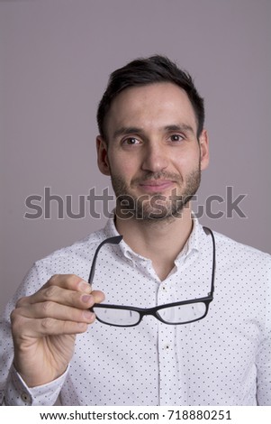 Portrait of a happy handsome young man. Holding black glasses.