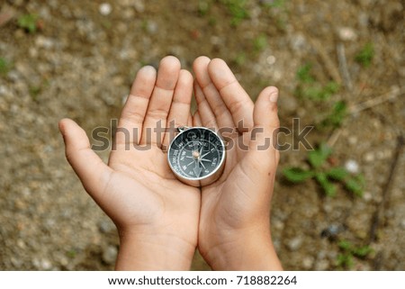 Hand holding a magnetic compass over nature background