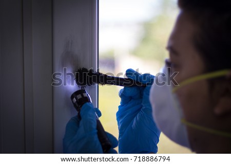 Forensic expert finds fingerprints on the window at the crime scene Royalty-Free Stock Photo #718886794
