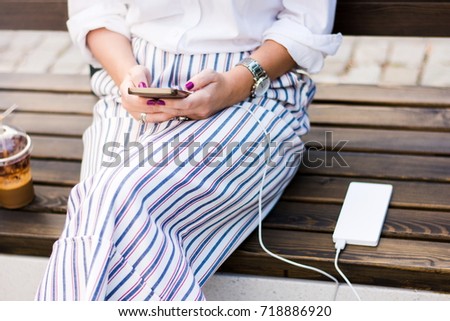 Girl using smart phone while charging on the power bank Royalty-Free Stock Photo #718886920