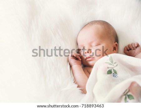 Sleeping newborn baby in a wrap on white blanket. Beautiful portrait of little child girl 7 days, one week old. Royalty-Free Stock Photo #718893463