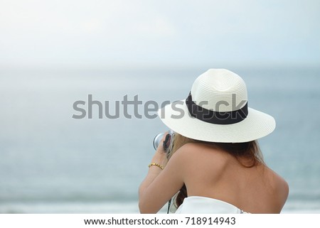 Asian woman wear hat ,hold camera and take photo on the sea view